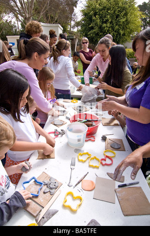 Un groupe d'enfants qui travaillent sur divers projets d'art connexes argile pendant un atelier d'art par des artistes locaux dans un parc Banque D'Images