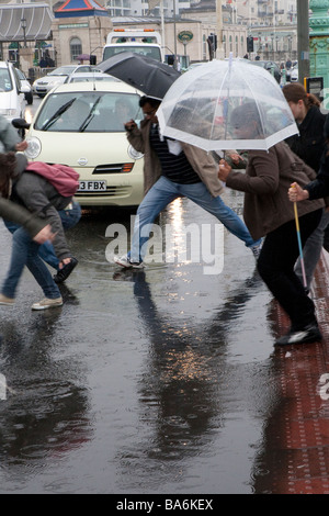 Les gens sautant par dessus les flaques d'eau de pluie en route inondée, Palace Pier, Brighton Banque D'Images