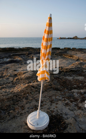 Fermé le jaune et blanc à rayures parasol peuplements dans petite baie sur la côte méditerranéenne espagnole sur tôt le matin Banque D'Images