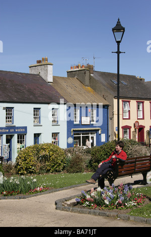 Ville de St David's, au Pays de Galles. Femme assise sur un banc dans le jardin commémoratif de guerre à Cross Square dans le centre de St David's. Banque D'Images