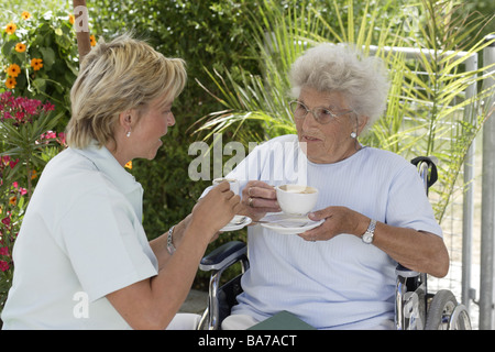 Accueil de la haute direction La haute terrasse gardien Kaffeetrinken en fauteuil roulant ensemble personnes seniors femme 70-80 ans 30-40 ans keeper Banque D'Images