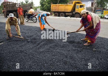 Les travailleurs masculins et féminins / ouvriers répandre sur une route asphaltée à Surat. Le Gujarat. L'Inde. Banque D'Images