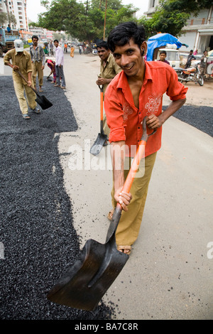 Homme ouvrier / ouvrier répandre sur une route asphaltée à Surat. Le Gujarat. L'Inde. Banque D'Images