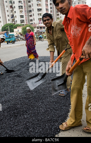 Homme ouvrier / ouvrier répandre sur une route asphaltée à Surat. Le Gujarat. L'Inde. Banque D'Images