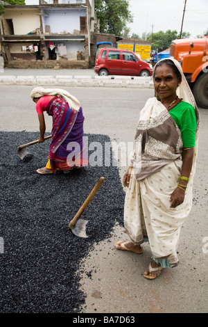 Femme / ouvriers ouvriers répandre sur une route asphaltée à Surat. Le Gujarat. L'Inde. Banque D'Images