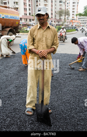 Homme ouvrier / ouvrier répandre sur une route asphaltée à Surat. Le Gujarat. L'Inde. Banque D'Images