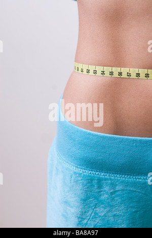 Young woman measuring waist with tape measure Banque D'Images