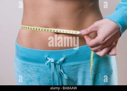 Young woman measuring waist with tape measure Banque D'Images