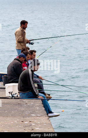 Les hommes la pêche au large du quai au port de Funchal Banque D'Images