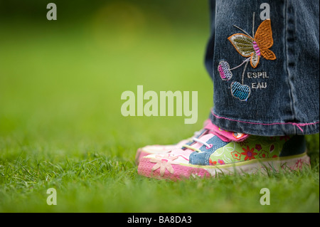 Plimsolls childs colorés sur une pelouse. UK Banque D'Images