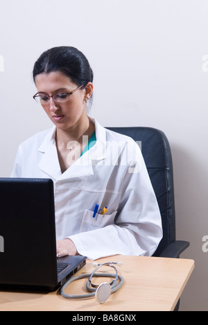 Doctor typing on laptop computer in office Banque D'Images