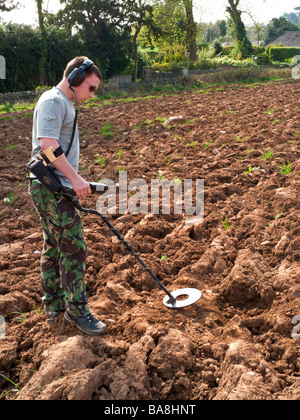 Homme avec détecteur de métal en champ labouré UK Banque D'Images