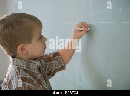 Garçon faire des mathématiques sur tableau noir Banque D'Images