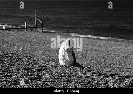 Une figure solitaire prend dans le soleil du printemps sur 'Beach' Norfolk Weybourne, UK Banque D'Images