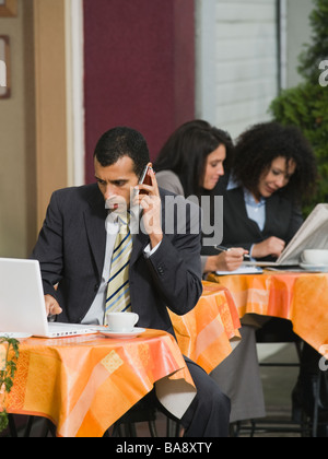 Businessman looking at laptop at outdoor cafe Banque D'Images