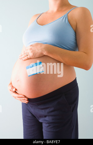 Femme enceinte avec l'étiquette-nom sur ventre bleu Banque D'Images