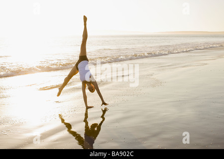 Woman doing cartwheel on beach Banque D'Images