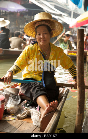 Une femme thaïlandaise portant un chapeau traditionnel thaïlandais sourires assis sur son bateau au marché flottant près de Bangkok en Thaïlande Banque D'Images