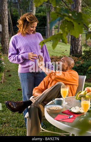 Couple afro-américaine ayant le petit déjeuner dehors, femme enceinte Banque D'Images