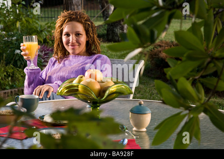 Femme afro-américaine assis à table d'extérieur ayant le petit déjeuner Banque D'Images