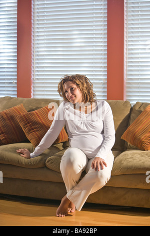 Afro-américaine enceinte woman sitting on sofa Banque D'Images