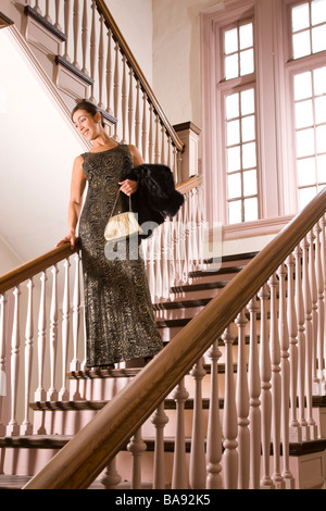 Hispanic woman in robe formelle debout sur les escaliers Banque D'Images