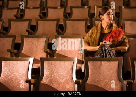 Hispanic woman in robe formelle assis dans le théâtre Banque D'Images