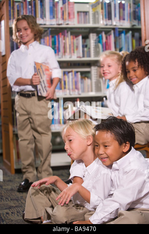 Cinq enfants de l'école primaire assis dans library Banque D'Images