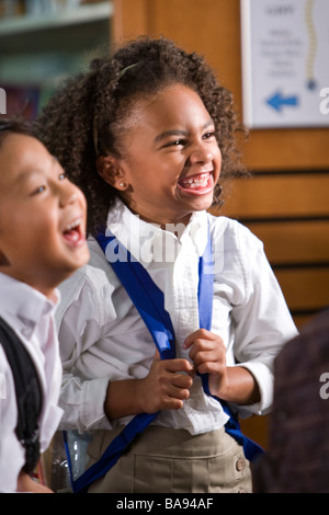 Les Asiatiques et les Africains-Américains les enfants de l'école élémentaire de rire dans la bibliothèque Banque D'Images