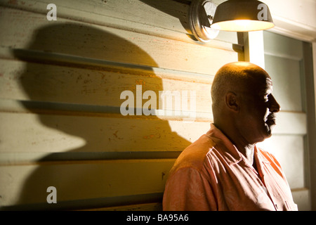 African American man standing on porche de maison la nuit Banque D'Images