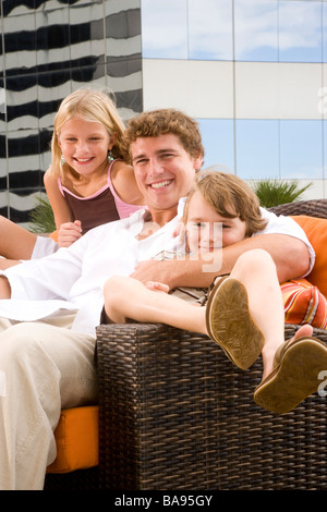 Deux enfants avec le père de détente sur terrasse sur le toit Banque D'Images