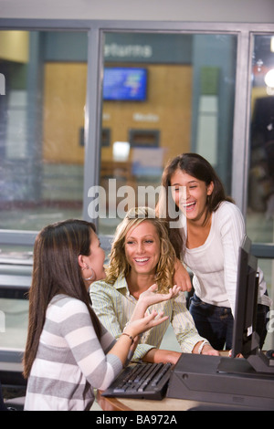 Trois amis de l'école secondaire à l'aide d'ordinateur laughing Banque D'Images