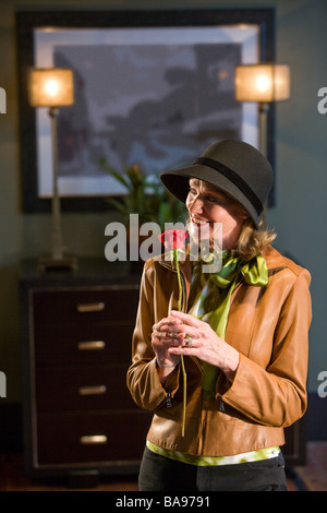 Middle-aged woman wearing hat holding red rose Banque D'Images