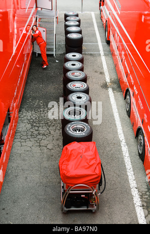 Pneus compétition slick empilés entre les camions de Formule Un Ferrari dans l'enclos Banque D'Images