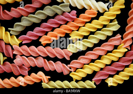 Différentes saveurs de pâtes fusilli torsades sur un fond noir. Banque D'Images