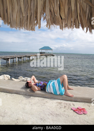 Jeune femme enveloppée dans une serviette sur la plage se relaxe au soleil sur une journée chaude sur Ambergris Caye à Belize Banque D'Images