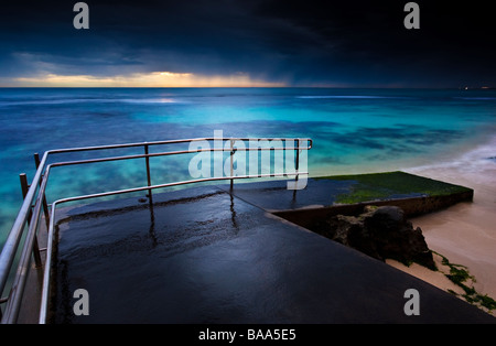 Ciel orageux au coucher du soleil sur la rampe à la pêche accessible en fauteuil roulant Mettam's Pool. Trigg Beach, Perth, Australie Banque D'Images