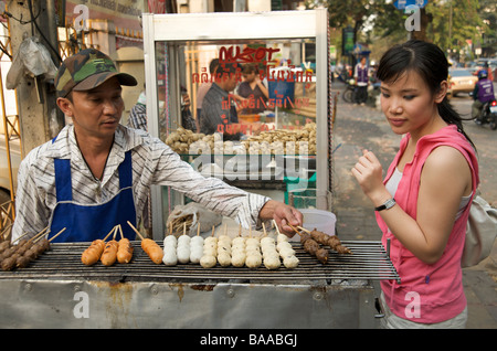 Une jeune fille thaïlandaise choisissant Bangkok meatballs d'un gril de rue Bangkok Thaïlande Banque D'Images