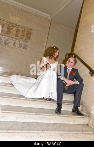 Grand angle vertical portrait de la nouvelle mariée mariée et le marié qui pose pour des photos sur un grand escalier de marbre formel Banque D'Images