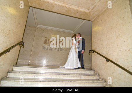Grand angle horizontal portrait de la nouvelle mariée mariée et le marié qui pose pour des photos sur un grand escalier de marbre formel Banque D'Images