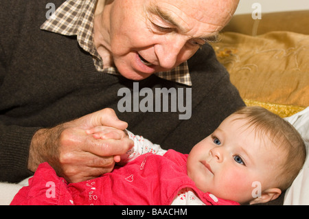 Close up portrait of horizontal d'un fier grand-père parlant doucement à sa belle-fille de bébé tout en tenant sa main Banque D'Images