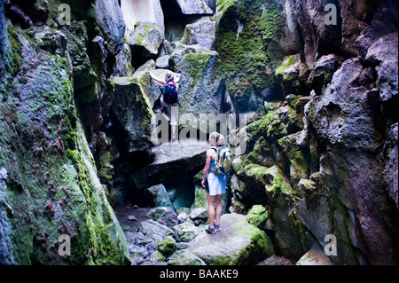 Deux femmes grimpent à travers une fissure dans le sol, une fissure volcanique près de christmas Valley, Oregon. Banque D'Images