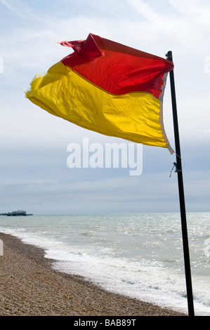 Un sauveteur en service d'un drapeau dans le vent souffle sur la plage de Brighton, Angleterre Banque D'Images