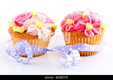 Paire de cupcakes avec fleurs et ruban de givrage Banque D'Images