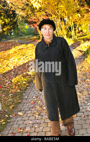 Senior woman de marcher seul dans le parc de l'automne Banque D'Images