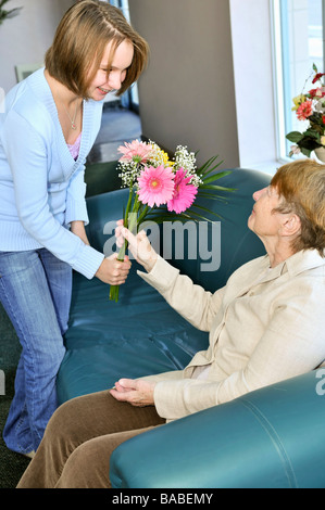 Petite-fille portant des fleurs colorées à sa grand-mère Banque D'Images