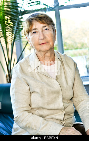 Triste femme âgée assise sur un sofa à l'intérieur Banque D'Images