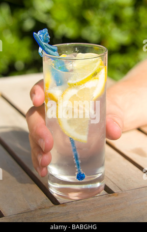 Main tenant le verre de Gin Tonic avec une tranche de citron et d'un mélangeur mermaid bleu Banque D'Images