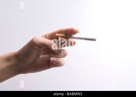 Woman's hand holding une cigarette sur un fond blanc. Banque D'Images