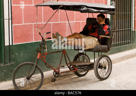 Pedicab driver prend une pause après une longue journée de travail à La Havane, Cuba. Banque D'Images